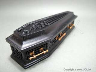 Black wooden coffin. brass handles on the sides. one little pillow 
